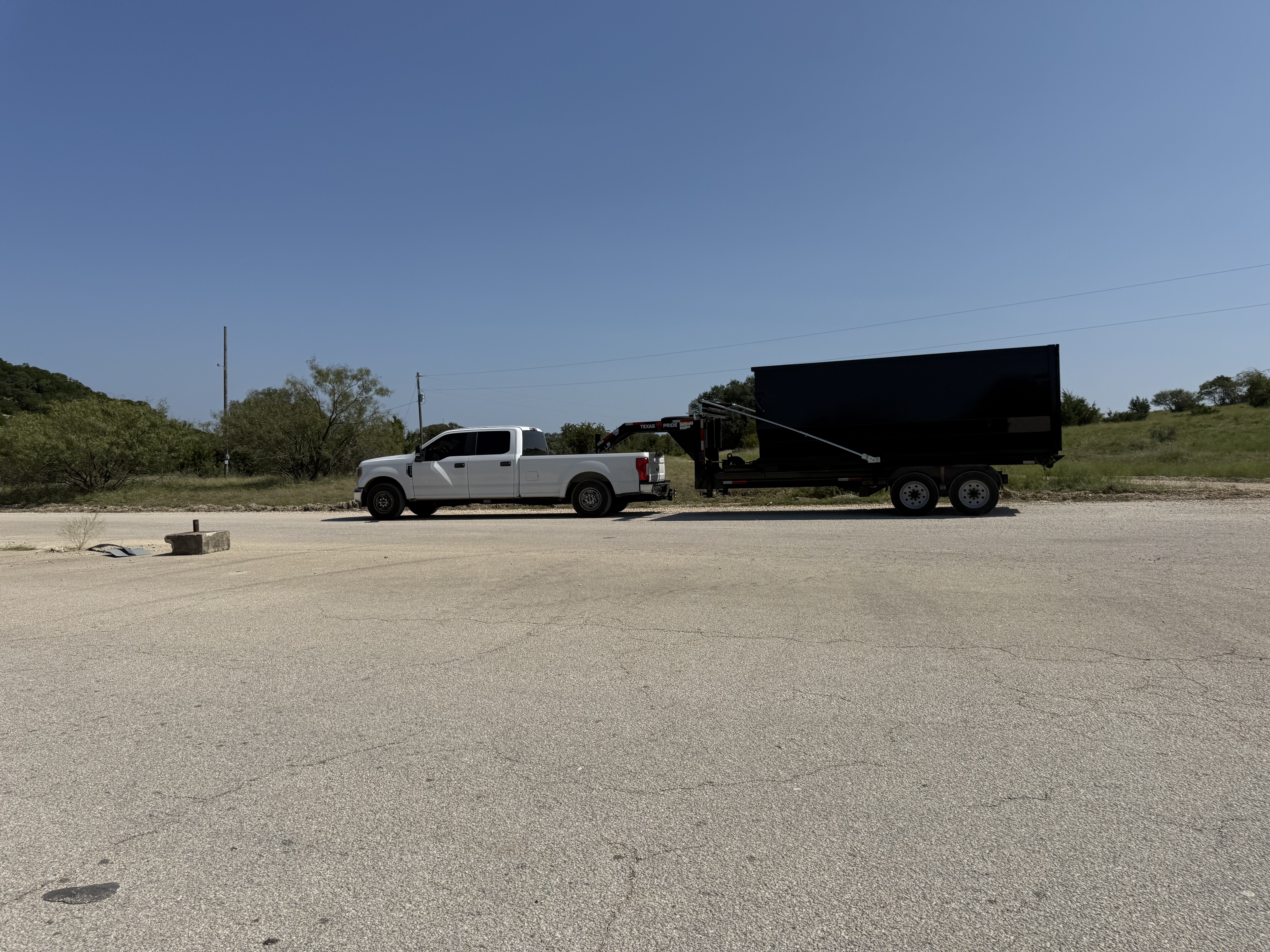 V5 Inc. truck hauling dumpster trailer on the road